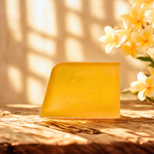 Savon Frangipanier Joa Savon dans une ambiance chaleureuse avec fleurs de frangipanier et lumière douce